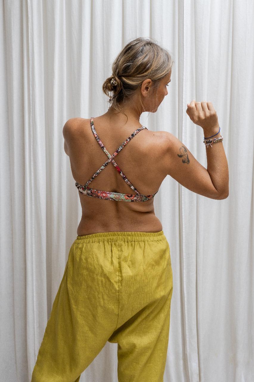 A woman standing against a white backdrop, wearing lemon green linen hipster pants and a bra. All Shivani Divine Wear.