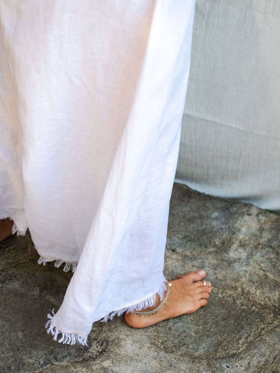A woman wearing a white maxi v-neck linen dress, detail.