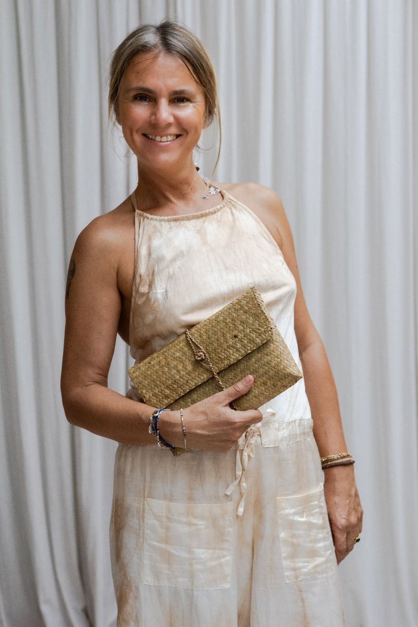 A woman wearing a beige silk romper with a halter neckline and wide-leg silhouette, tea-dyed for earthy tones.