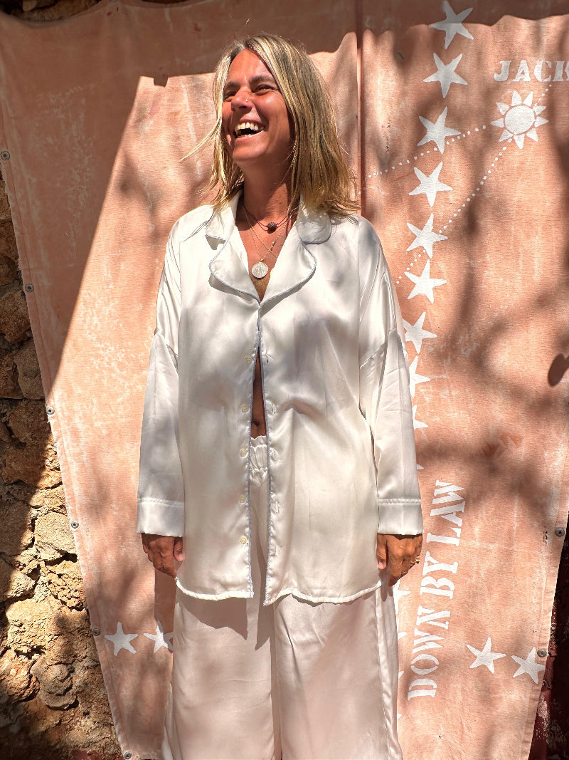 Woman wearing white shivani pajama set standing against a decorative backdrop with 'JACK by BB Dakota' branding.