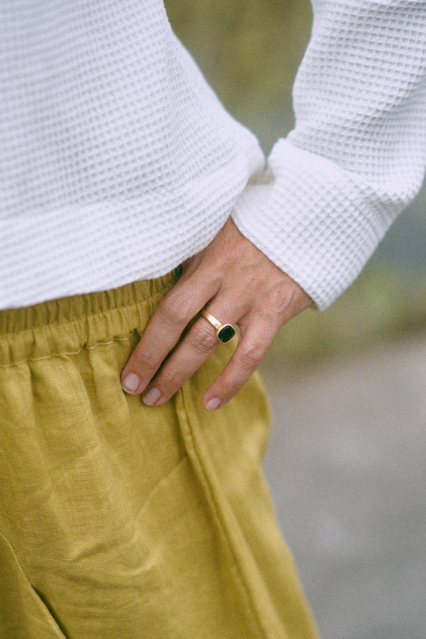 A woman wearing a white hoodie with a zipper and a flowing hood, paired with yellow pants. Detail view.