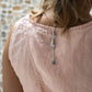 A woman wearing a sleeveless pink top standing against a textured wall. Detail.