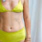 This image features the KAVERI Bikini, a beautifully designed swimwear piece that exudes elegance and spirit. The bikini comes in a striking shade of lime green, reminiscent of vibrant tropical waters and lush earth tones.