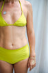 This image features the KAVERI Bikini, a beautifully designed swimwear piece that exudes elegance and spirit. The bikini comes in a striking shade of lime green, reminiscent of vibrant tropical waters and lush earth tones.