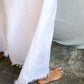 A woman wearing a white maxi v-neck linen dress, detail.