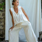 A woman modeling flowy white silk pants with a straight-leg silhouette and a soft elastic waistband.