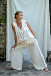 A woman modeling flowy white silk pants with a straight-leg silhouette and a soft elastic waistband.
