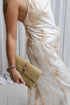 A woman wearing a beige tea-dye elegant silk romper with a halter-style neckline and wide-leg silhouette, standing with a white backdrop in the background. Close up view.