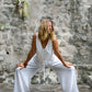 This image features the SHUCKI Romper in a serene, outdoor setting. The romper, crafted from a blend of white cotton, is showcased in a gentle V-neckline and a drawstring waist, highlighting its versatile and comfortable design.
