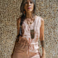 A woman wearing a rose pink linen romper with wide legs and a V-neckline, standing against a textured background.
