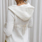 A woman wearing a white hoodie with a zipper and a flowing hood, paired with yellow pants. Back view