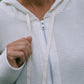 A woman wearing a white hoodie with a zipper, detail view.