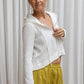 A woman wearing a white hoodie with a zipper and a flowing hood, paired with yellow pants.