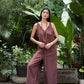 Woman in a brown linen jumpsuit standing in a lush garden