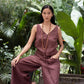 Woman in a linen jumpsuit sitting among tropical plants