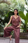 Woman in a linen jumpsuit sitting among tropical plants